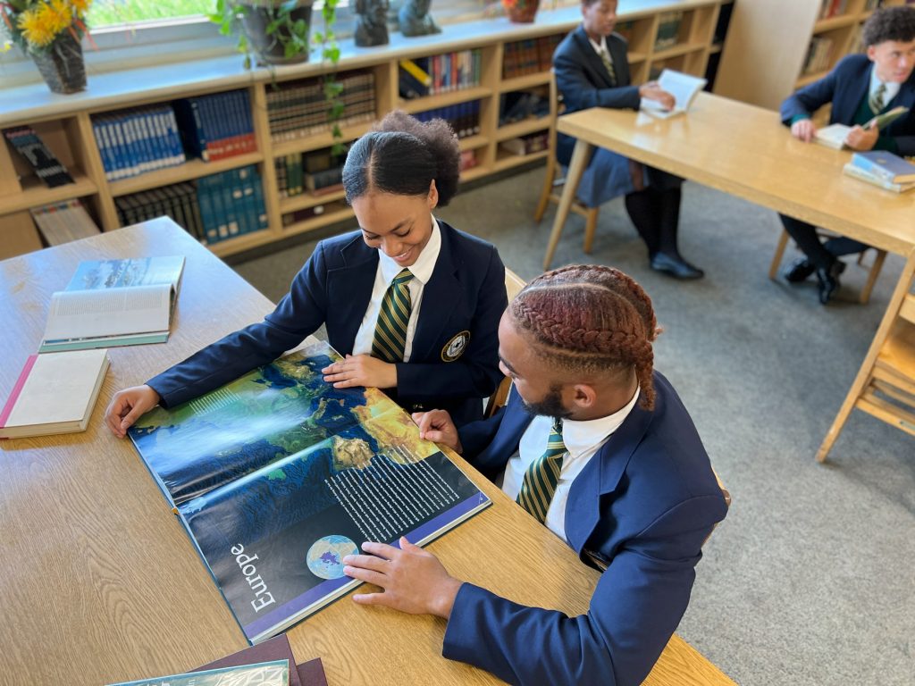 Two Students Looking at an Atlas of Europe